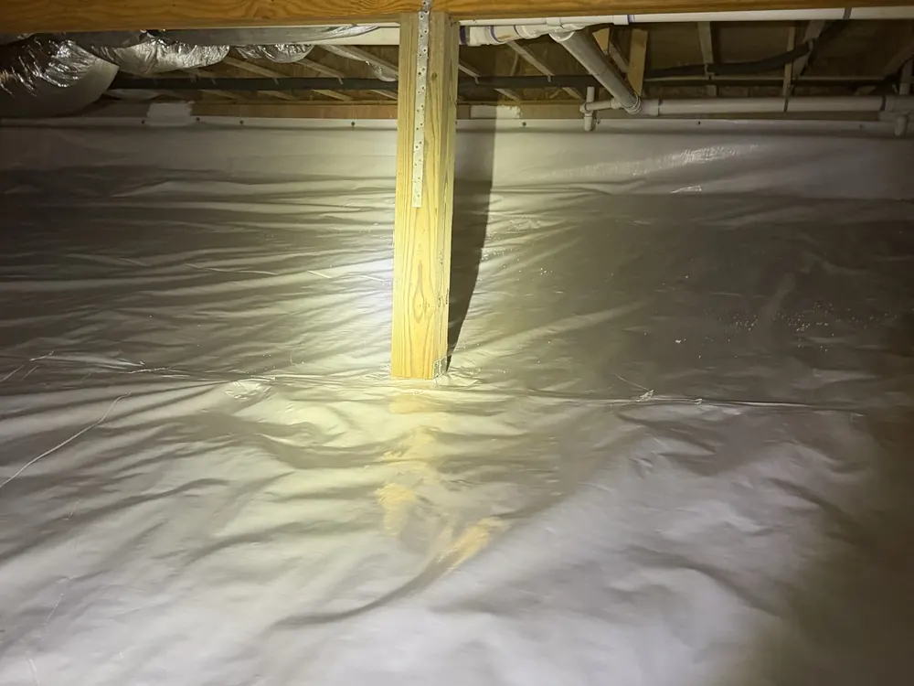 A finished white crawl space liner around a support post under the floor framing