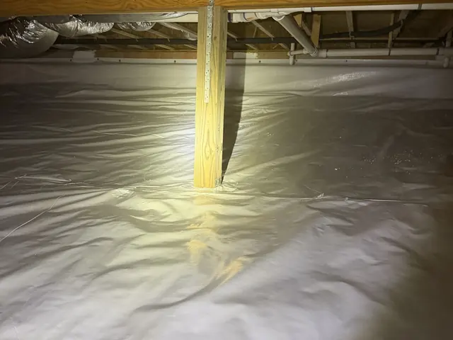 A finished white crawl space liner around a support post under the floor framing