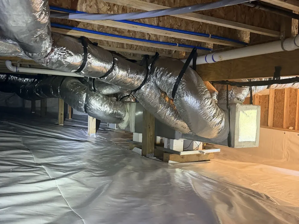A finished crawl space: white liner on the floor under insulated ductwork