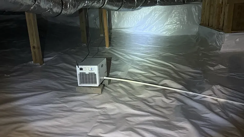 Crawl space after: a dehumidifier sitting on the sealed white liner