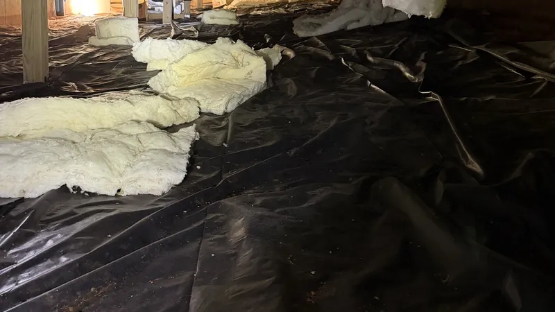 Before: insulation batts fallen out of the floor onto black plastic